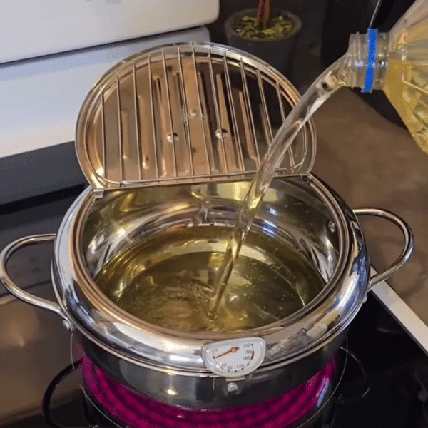 Persona friendo papas en una olla freidora japonesa con termómetro